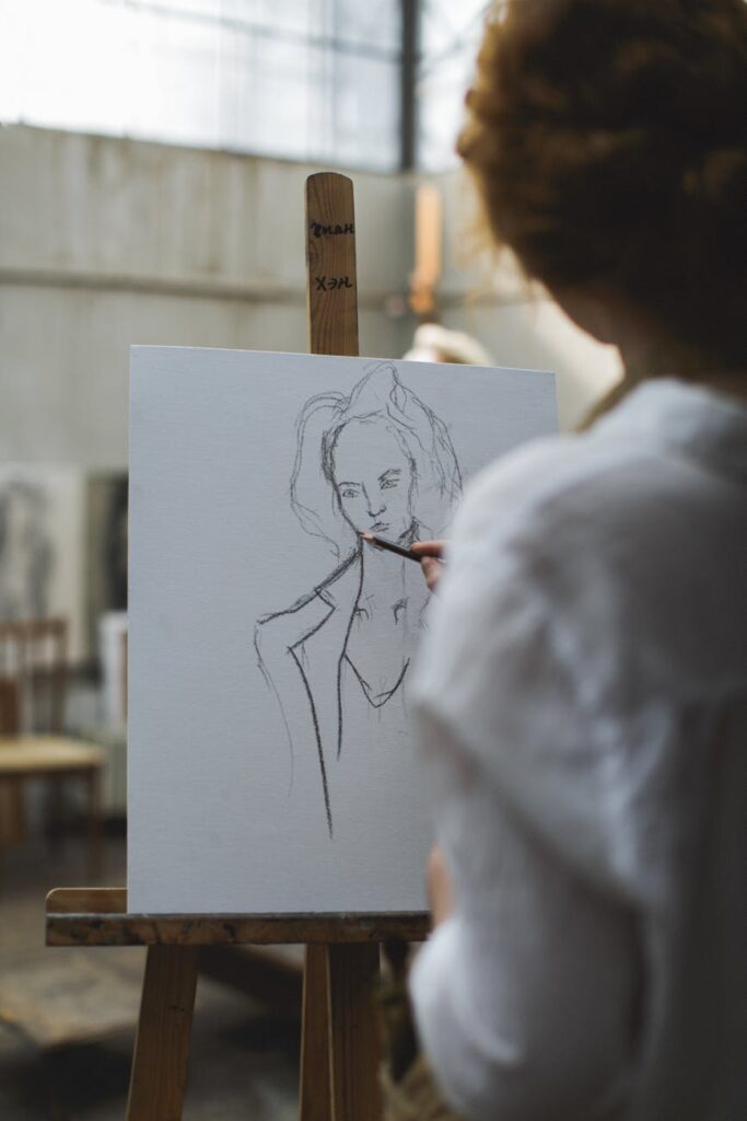 woman in white shirt sketching on paper