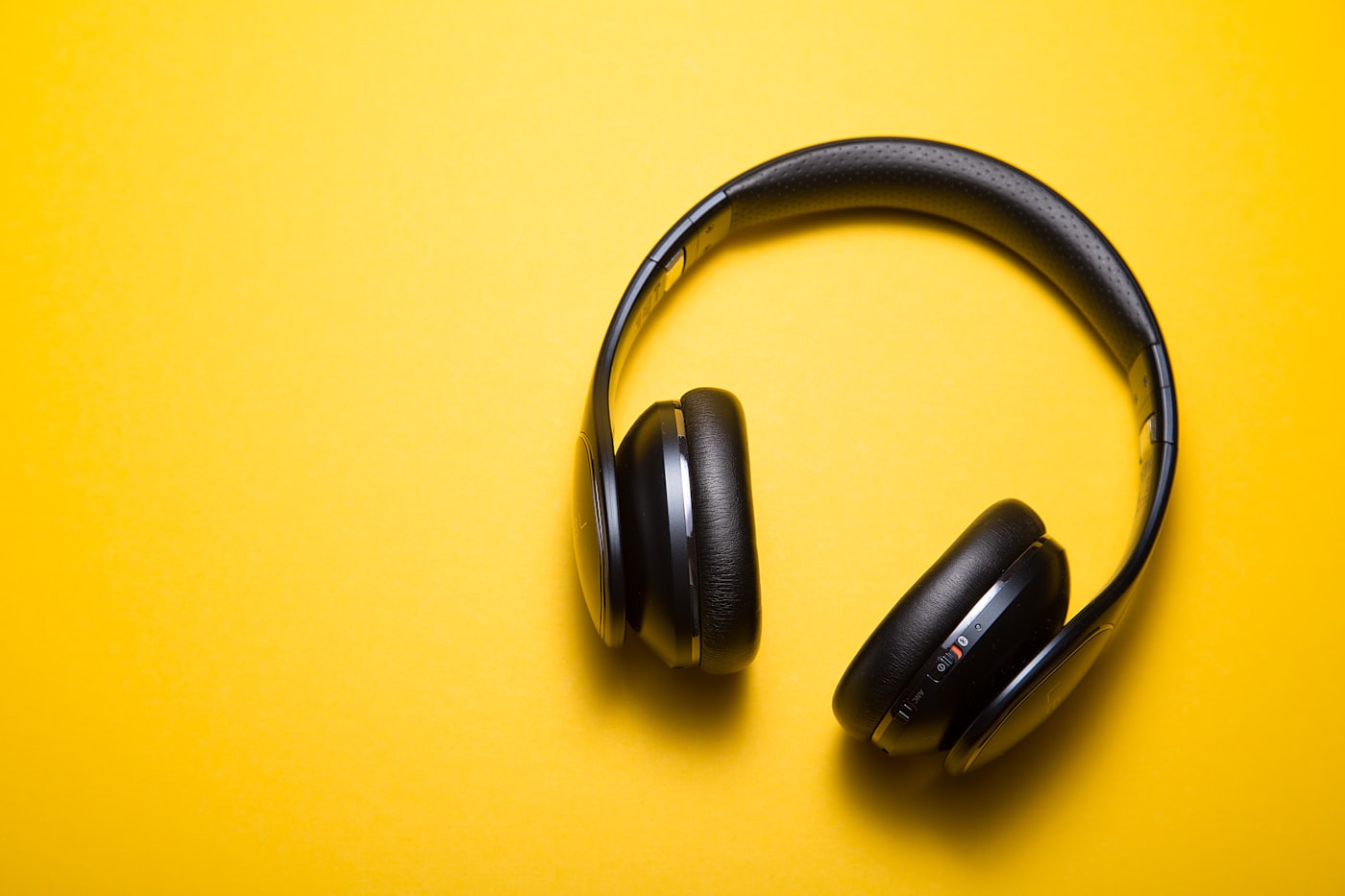 Fones de ouvido sobre fundo amarelo representando o consumo de música em plataformas digitais